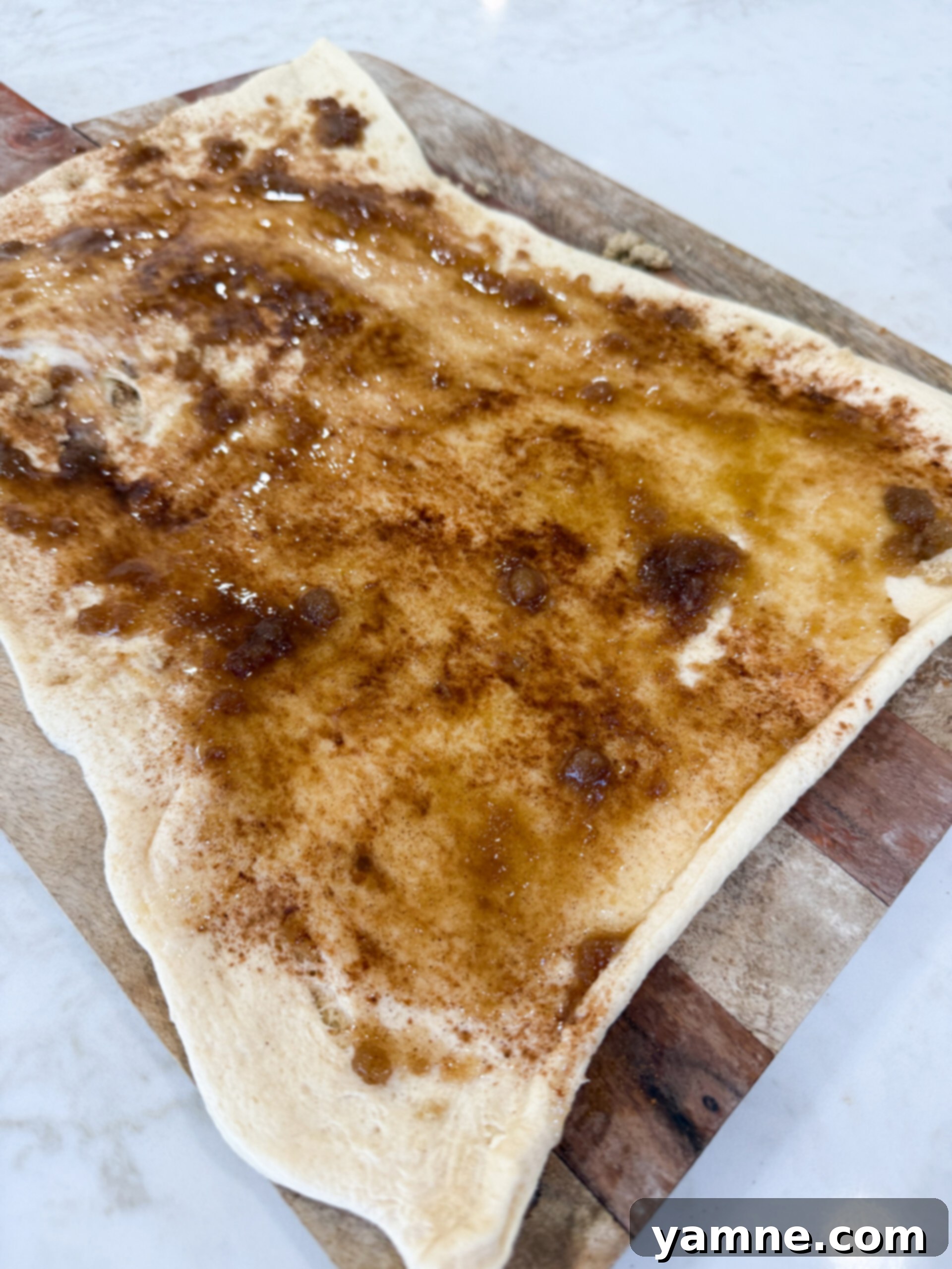 Sprinkling cinnamon sugar over crescent dough