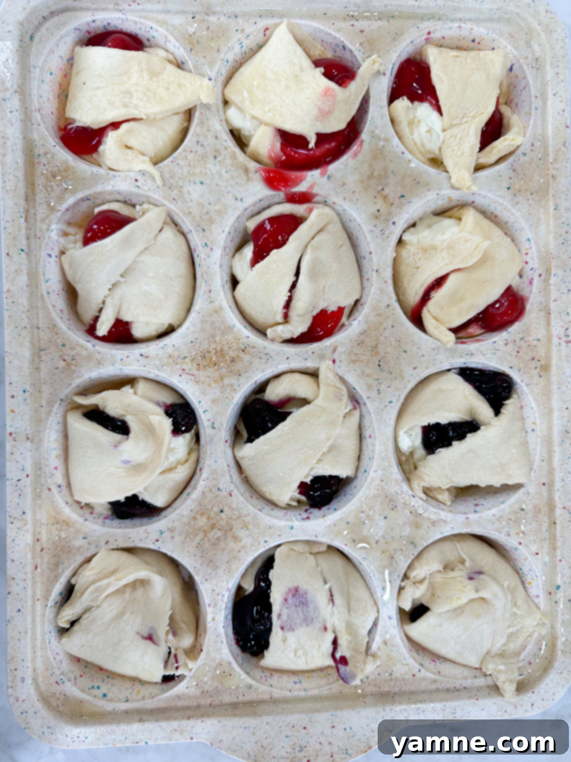 Crescent dough edges are folded inward over the cheesecake and fruit filling, partially covering the top.
