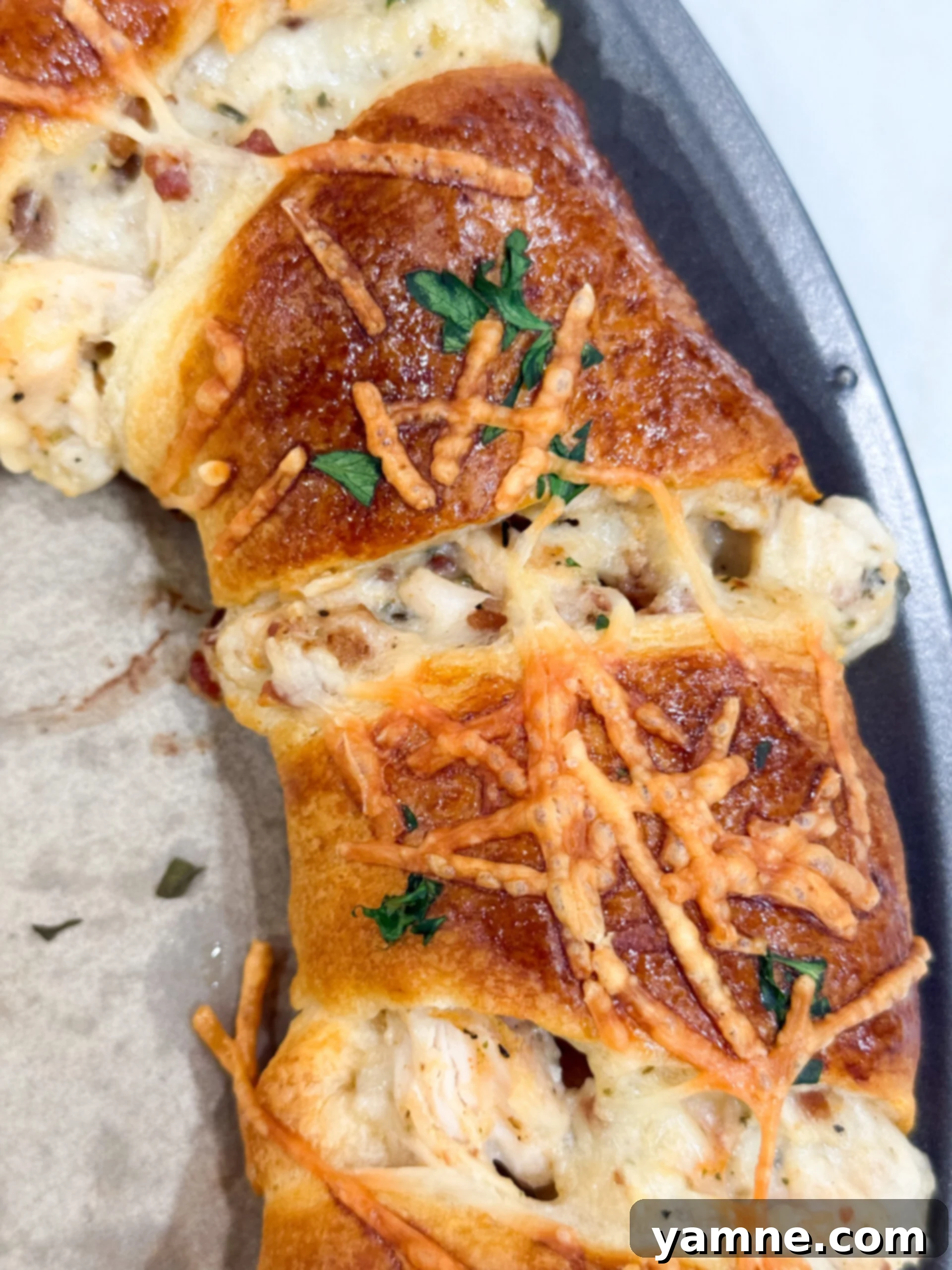 Golden crescent ring filled with chicken, bacon, and Alfredo sauce, ready to be sliced and served.