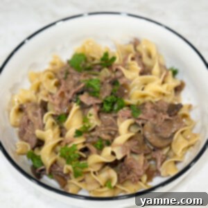 Easy Slow Cooker Beef Stroganoff 12 Slow cooker beef stroganoff served with noodles and fresh parsley garnish