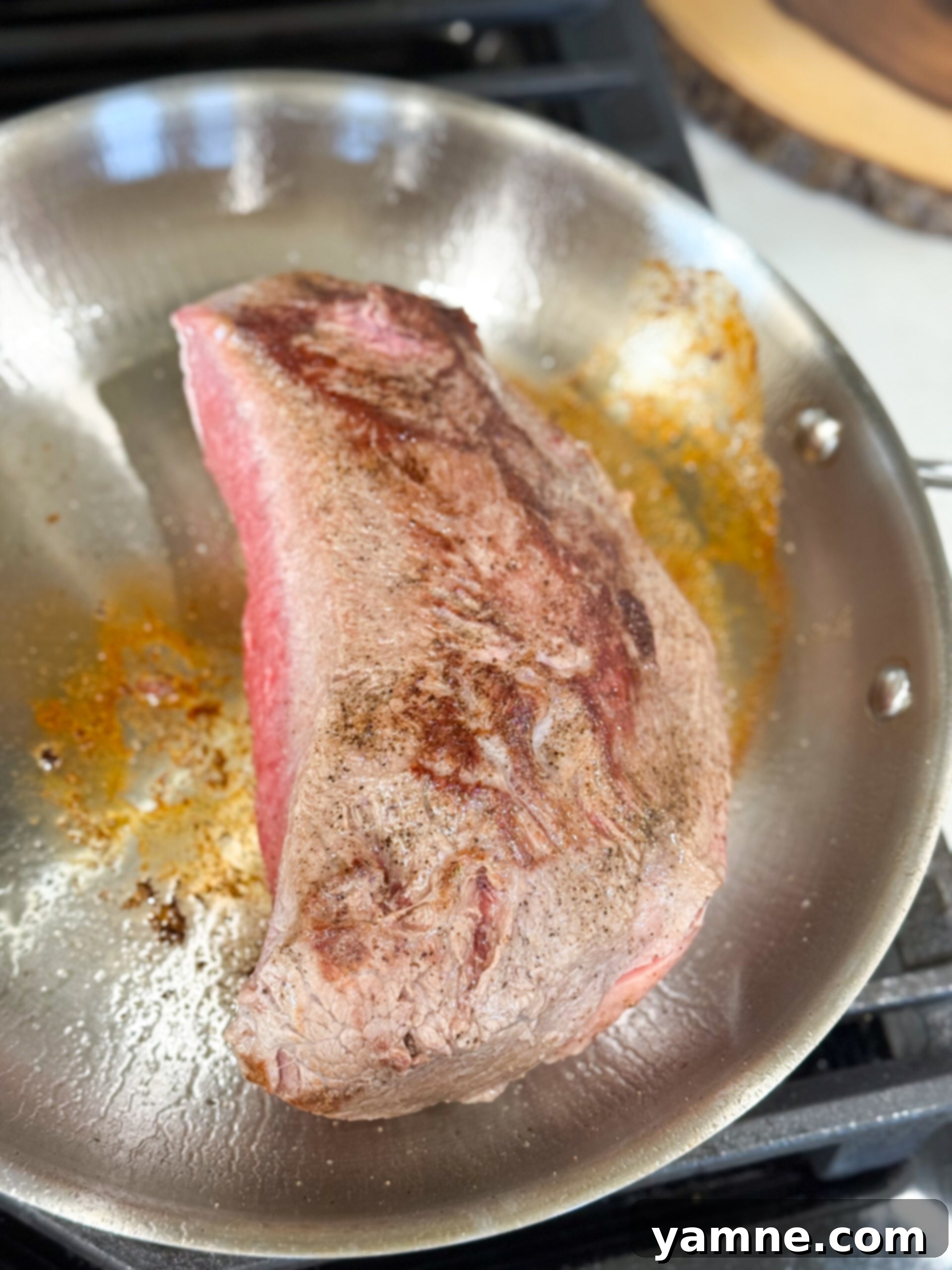 Easy Slow Cooker Beef Stroganoff 6 Searing a seasoned chuck roast in a cast iron skillet, browning the exterior before slow cooking.