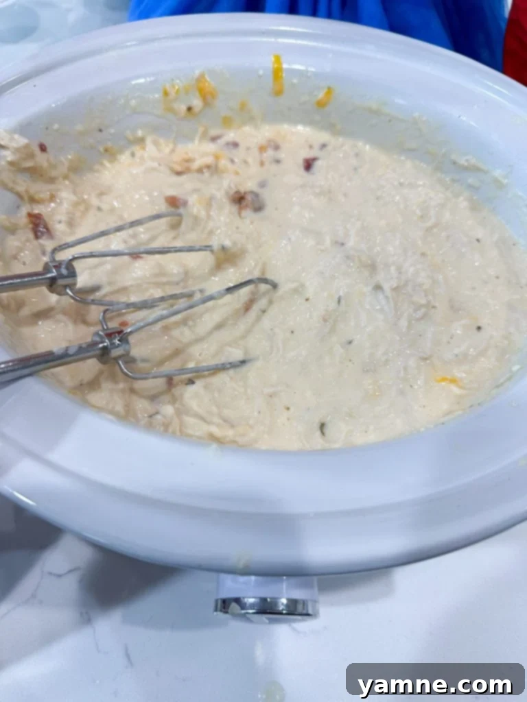 Shredded crack chicken with melted Colby Jack cheese in a slow cooker