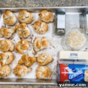 Irresistible Garlic Knots 2 Delicious golden brown garlic knots brushed with butter and herbs on a parchment-lined baking sheet, ready to be served