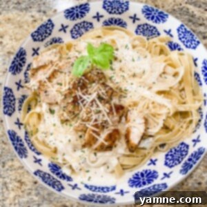 A plate of creamy chicken alfredo with fettuccine pasta, garnished with fresh parsley.