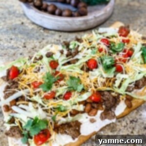 Tex-Mex Pizza 2 Delicious and vibrant Taco Pizza, freshly baked and topped with seasoned beef, crisp lettuce, diced tomatoes, and melted cheese on a flaky crescent roll crust.