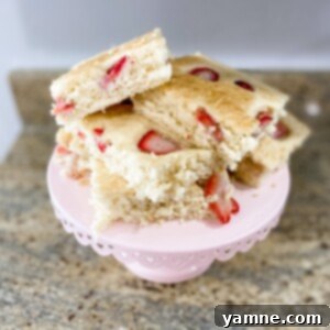 A delicious sheet pan pancake topped with fresh berries, cut into squares.