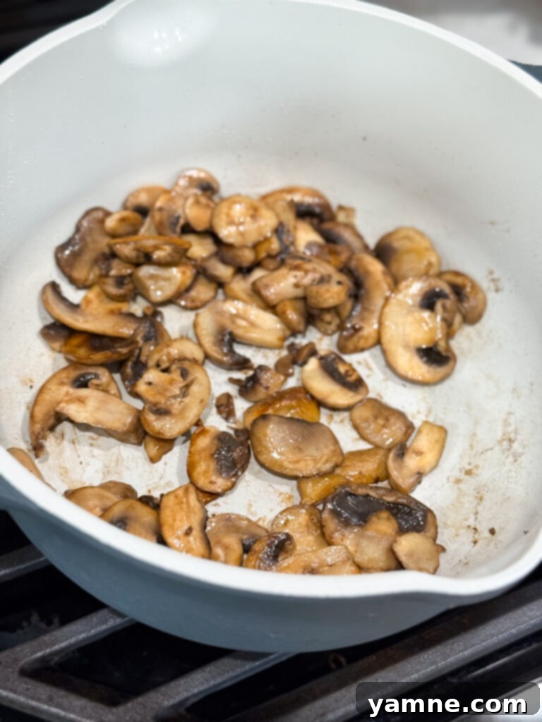 Sliced mushrooms sauteed until golden brown in a large skillet, forming the base of the stroganoff.