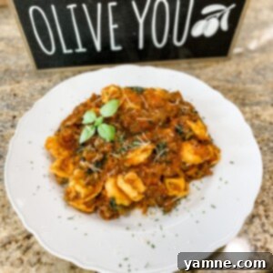One Pot Creamy Sausage Tortellini served in a skillet, garnished with fresh basil leaves