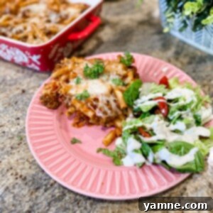 A deliciously cheesy baked ziti dish, fresh from the oven, garnished with herbs.