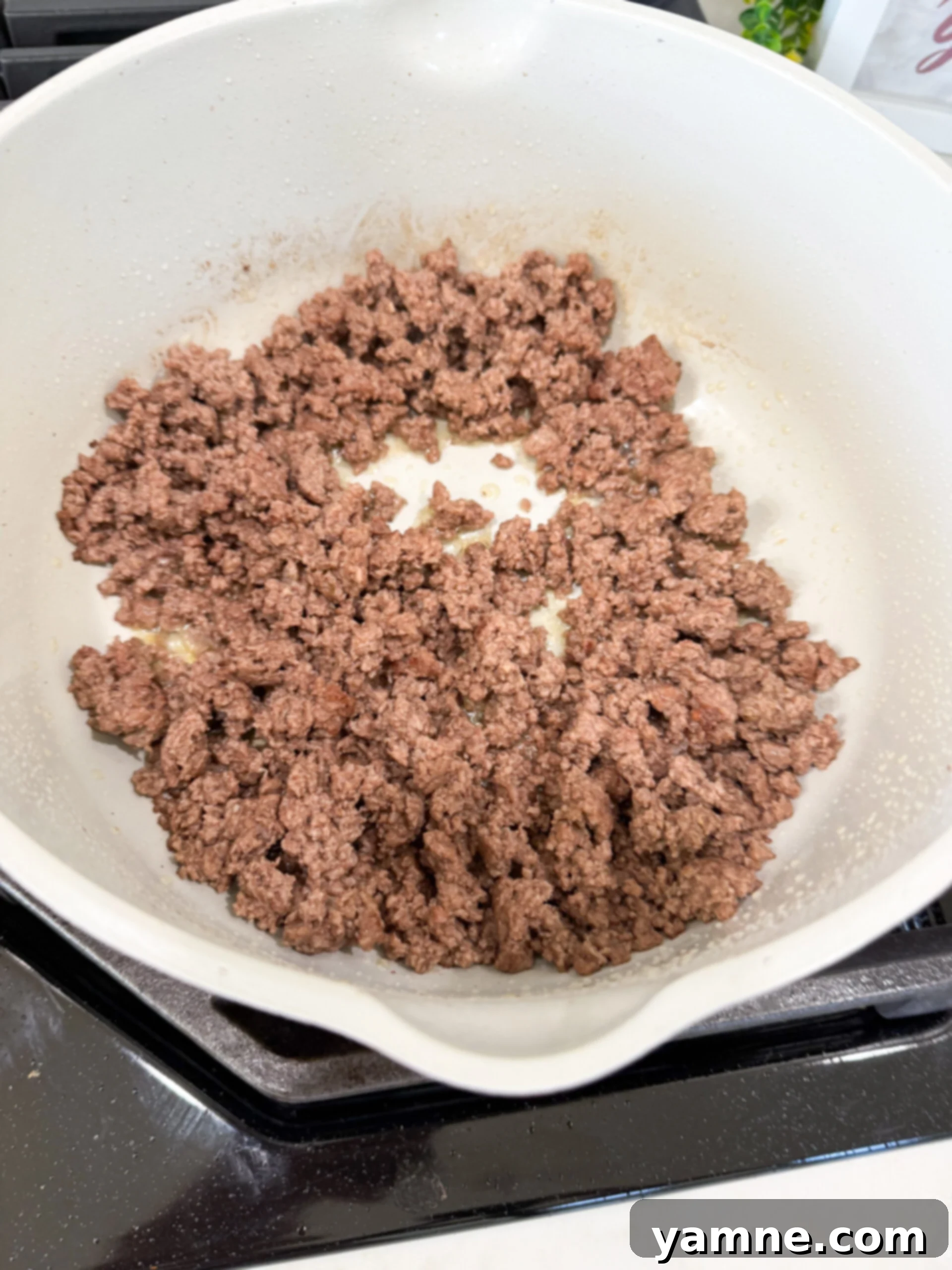 Ground beef browning in a large pot for taco pasta.
