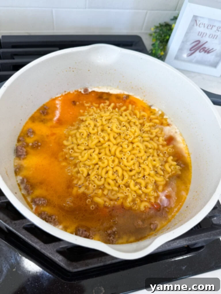 Taco pasta recipe cooking in a pot with cheese just stirred in.