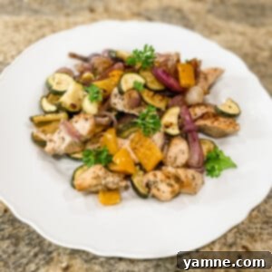 A vibrant sheet pan meal featuring seasoned chicken and roasted zucchini, bell peppers, and red onion, ready to serve.
