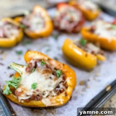 Close-up of vibrant stuffed bell peppers on a sheet pan, topped with melted cheese and fresh herbs, ready to serve.