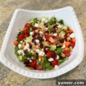 Crisp Garden Salad 2 A vibrant, fresh classic side salad with spinach, carrots, cherry tomatoes, avocado, green onions, feta, and a crunchy topping.
