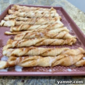 Scrumptious Cinnamon Twists 2 Delicious golden cinnamon twists drizzled with a sweet glaze, perfect for a quick snack or breakfast.