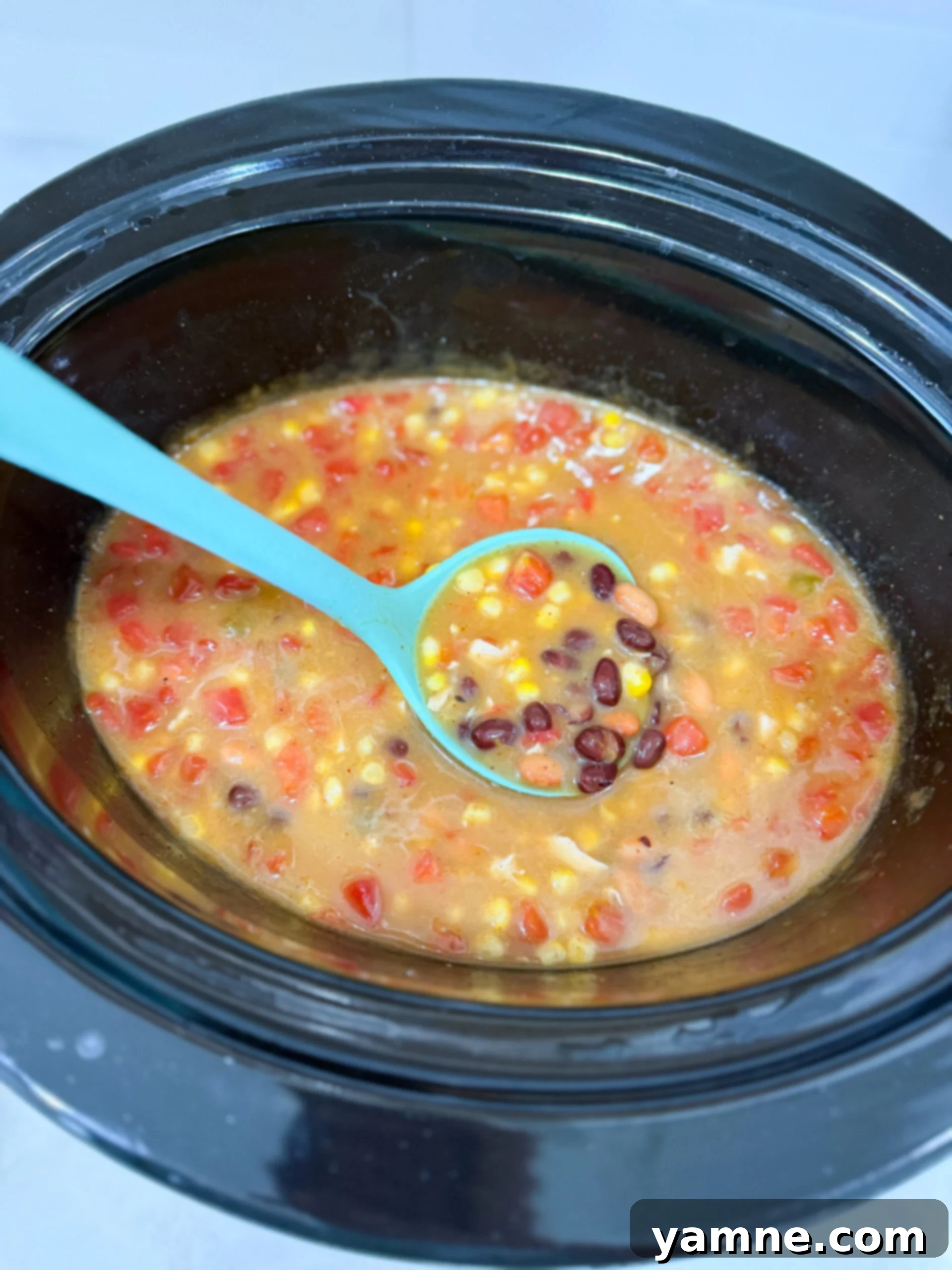 Soup cooking in slow cooker with beans, corn, and chicken