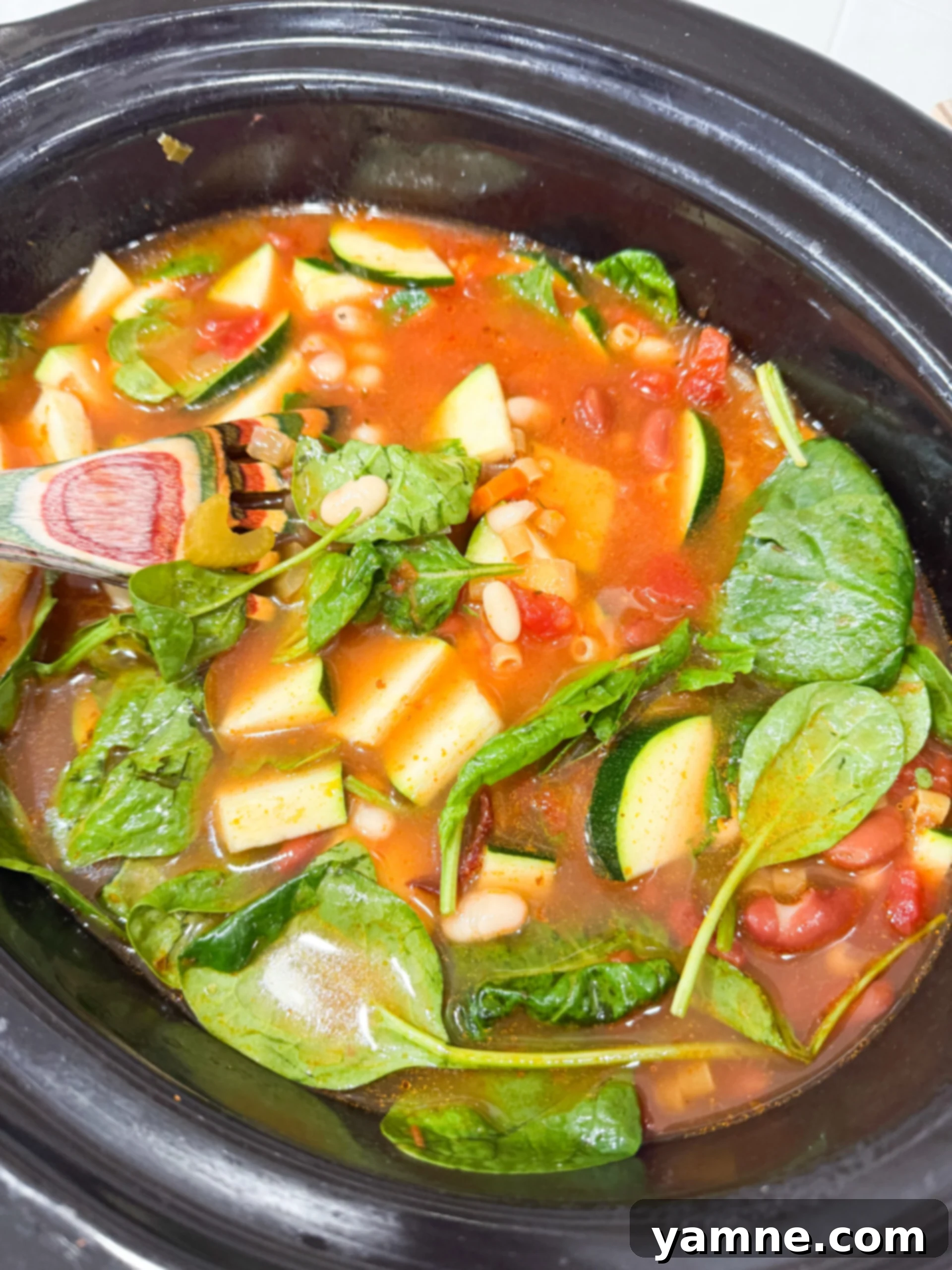 Stirring pasta and spinach into slow cooker soup