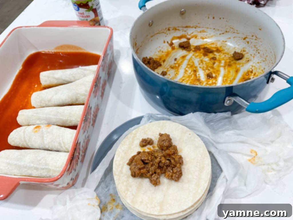Cooked ground beef filling with melted cheese and seasonings in a skillet, ready for enchilada assembly.