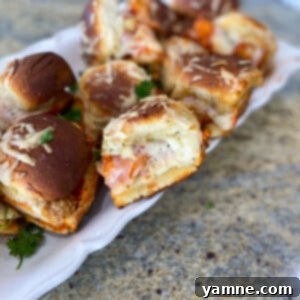 Close-up of golden brown Chicken Parmesan Sliders with melted cheese and herbs, ready to serve.