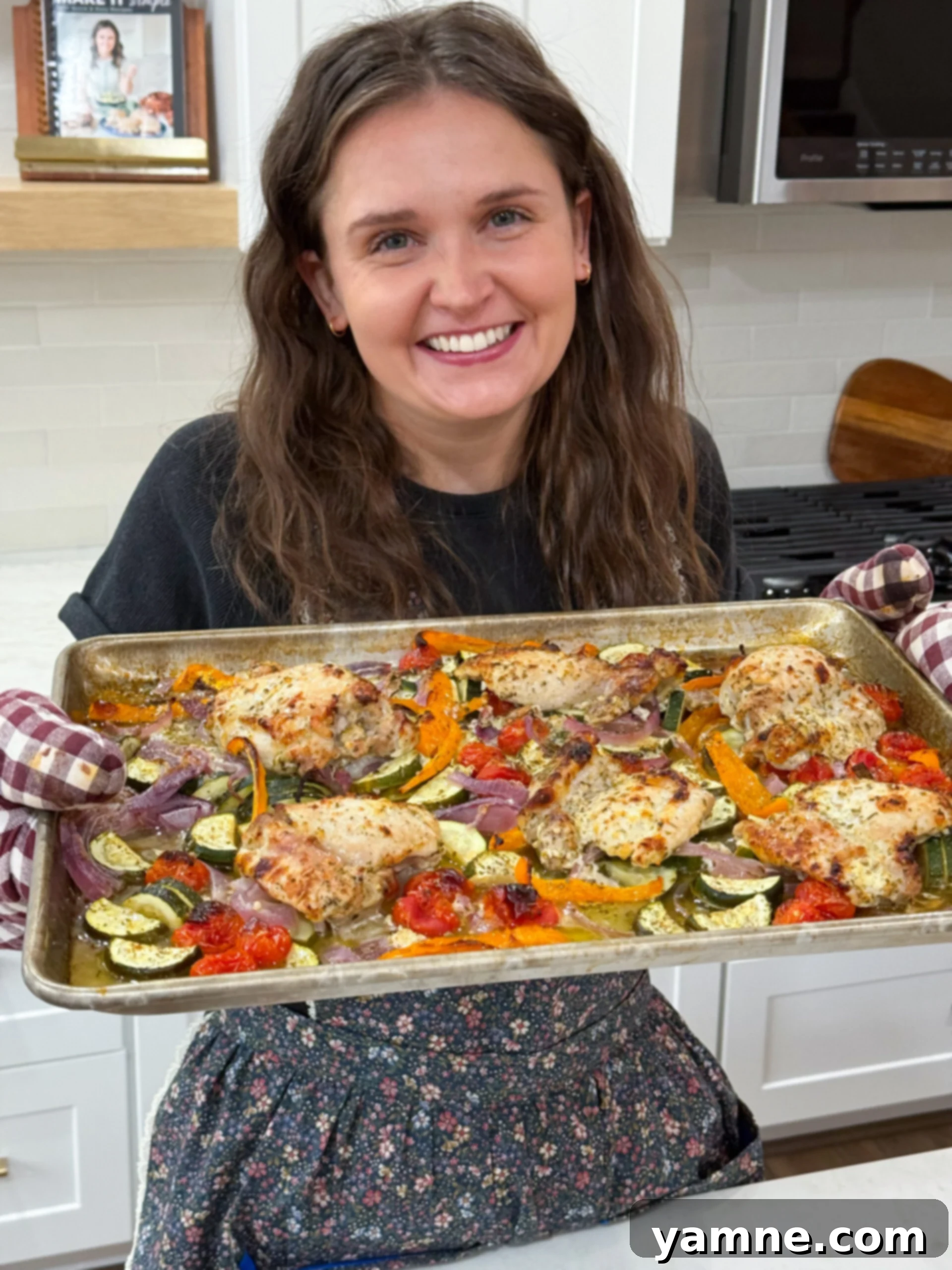 Chef holding finished sheet pan of greek chicken meal